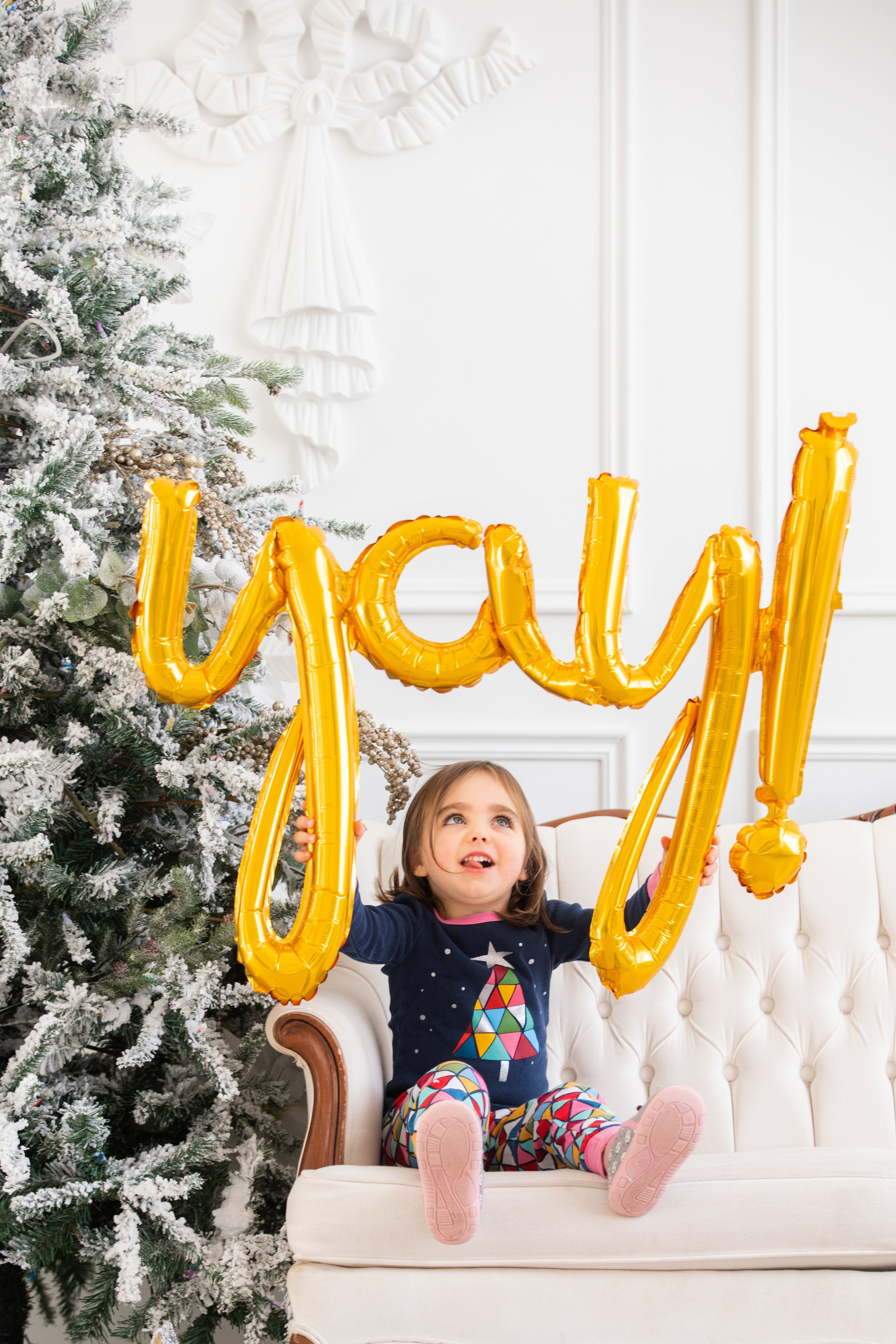 Girl holding yay Christmas balloon 